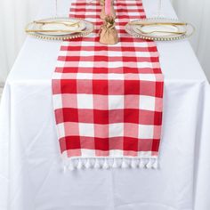 a red and white checkered table cloth on a dining room table with gold place settings