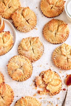 several small pies on a table next to a jar of jam and a spoon