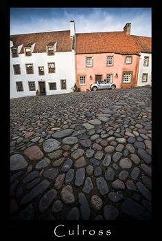 an old cobblestone street with cars parked in the background