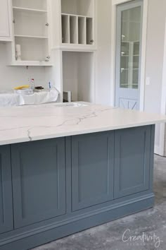 a large kitchen island in the middle of a room with white cabinets and marble counter tops