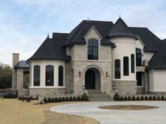 a large white house with black roofing and two story windows on the front of it