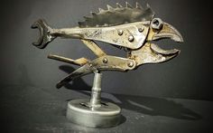 a metal sculpture of a fish on a stand with two pliers attached to it