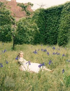 a woman laying in the grass with blue flowers