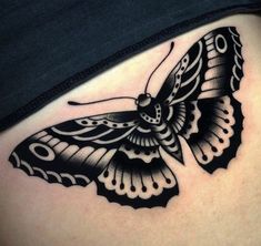 a black and white butterfly tattoo on the side of a woman's stomach,