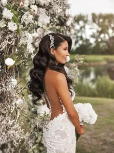 a woman in a wedding dress standing next to a tree with white flowers on it