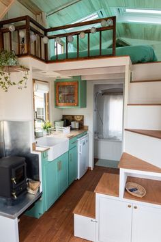 a tiny kitchen with stairs leading up to the loft above it and a stove top oven