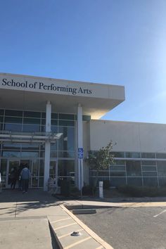 the front entrance of a school with people entering and exiting from it on a sunny day