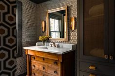 a bathroom with black and white wallpaper, gold accents and a wooden vanity sink