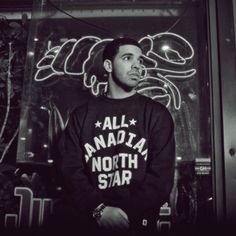 a man standing in front of a neon sign wearing a black sweatshirt that says, all anada north star