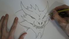 someone is drawing a dragon face on paper