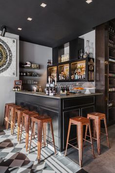 a bar with stools and bottles on the shelves