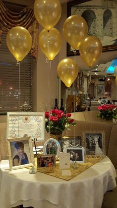 balloons are hanging from the ceiling above a table with pictures and flowers on it in front of a mirror