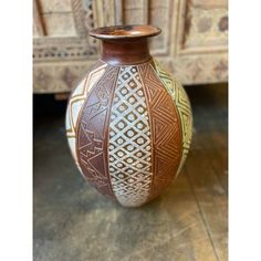 a brown and white vase sitting on top of a wooden floor