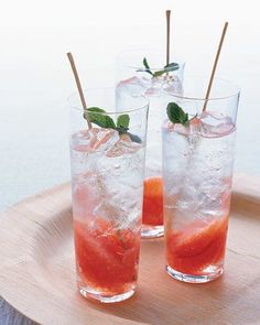 two glasses filled with watermelon and garnish on top of a wooden tray