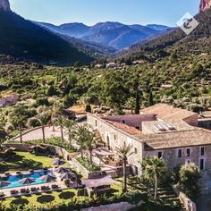 an aerial view of a house with mountains in the background and pool surrounded by greenery