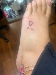 a woman's foot with a tattoo on it and stars around the ankle area