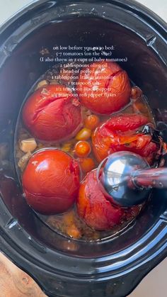 tomatoes and other vegetables are being cooked in the crock pot with a spoon to stir them