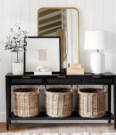 a black table with baskets on it and a mirror in the background that says,