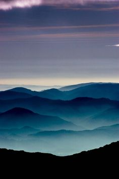 the mountains are covered in blue haze as the sun sets over them and there is no image to provide a caption for