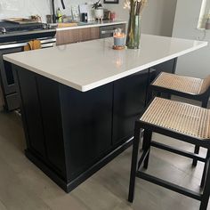 a kitchen island with two chairs next to it and a vase filled with flowers on top