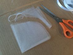 a pair of scissors sitting on top of a cardboard box next to some white fabric