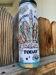 a white and blue water bottle sitting on top of a wooden shelf next to a fence