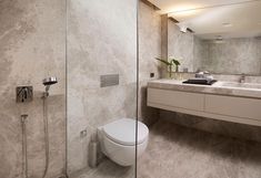 a bathroom with a toilet, sink and shower head mounted to the side of the wall