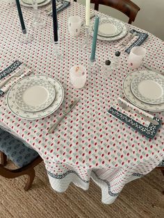 the table is set with white and red plates, silverware, and blue candlesticks