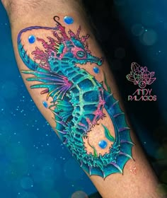 a blue and green dragon tattoo on the leg, with bubbles around its body in the background