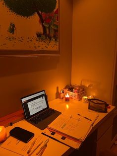 an open laptop computer sitting on top of a desk next to a lit up candle