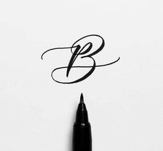 a pen writing the letter b on top of a piece of paper with black ink