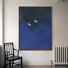 two birds are flying in the blue sky above a chair and radiator, against a white wall