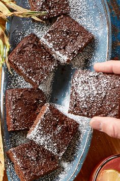 a person holding a piece of chocolate cake in front of some other pieces on a plate