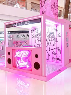 a pink machine with graffiti written on the front and sides, in an indoor area