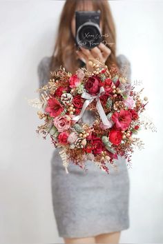 a woman taking a photo with her camera and holding a wreath in front of her face