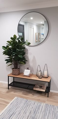 a mirror on the wall above a table with a potted plant next to it