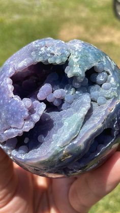 a person holding up a piece of rock with blue and purple crystals on it's surface