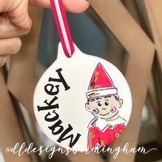 a person holding up a christmas ornament with a elf on it