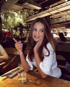 a woman sitting at a table with a glass of wine