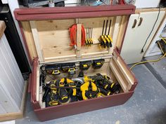 a tool box filled with lots of tools on top of a floor next to cabinets