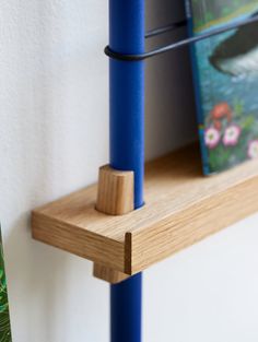 a wooden shelf with two books on it and a book holder attached to the wall