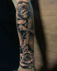 a person with a cross and roses on their arm