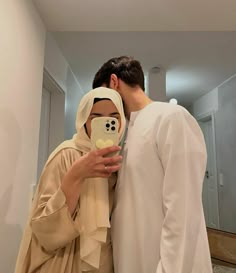 a man and woman are dressed up as jesus and mary in the bathroom, one is holding a cell phone