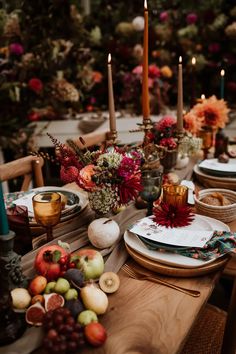 the table is set with plates, fruit and candles for an autumn dinner party or celebration