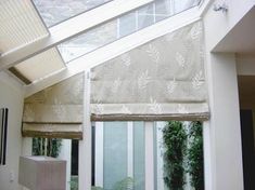 a room with a window covered in roman shades and plants on the windowsills