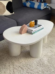 a white coffee table sitting on top of a rug in front of a gray couch