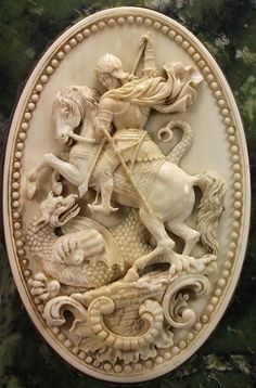 a carved white plaque with an image of a man on horseback riding a dragon and other animals