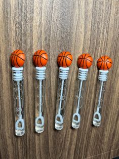 four plastic basketballs are in the shape of tubes on a wooden surface with metal handles