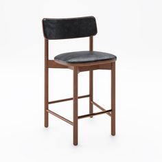 a wooden chair with black leather upholstered seat and back rests against a white background