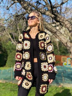 a woman standing in front of a tree wearing a black sweater and leggings